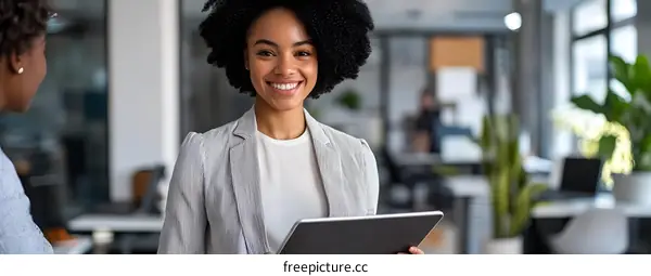 Smiling Black Businesswoman Holding a Tablet in an Office