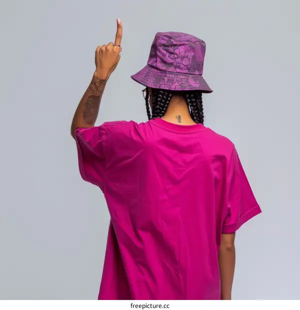 woman in purple shirt and hat holding up one finger