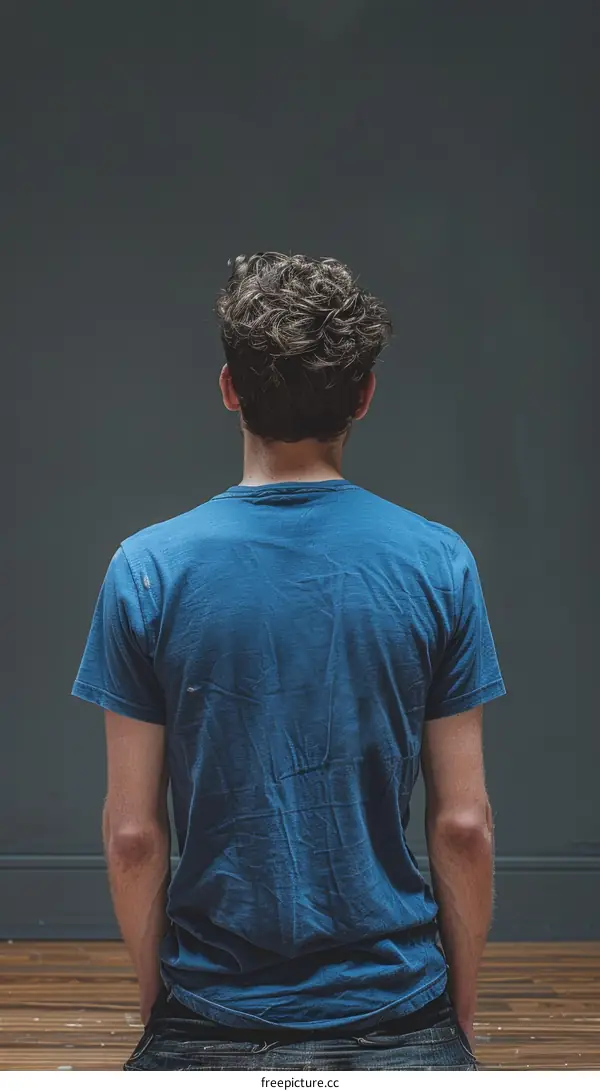 man with curly hair wearing blue t-shirt and jeans