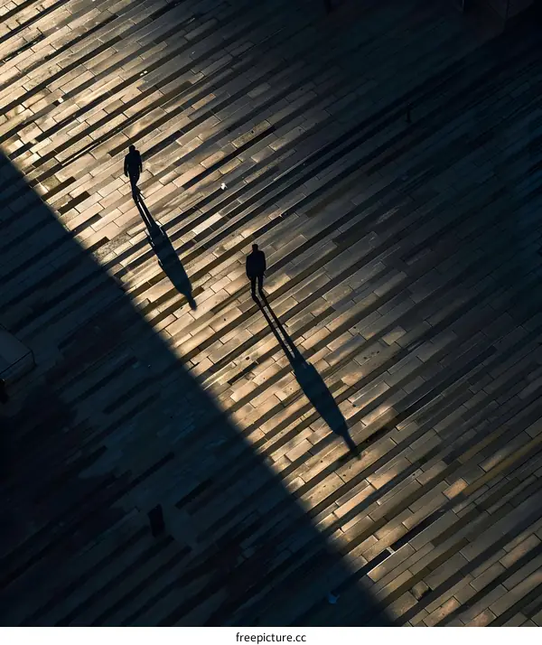 Two People Walking On A Pavement In The City, Silhouette With Long Shadows