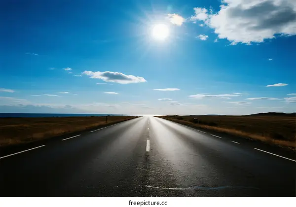 A clear road under the bright sun with some clouds