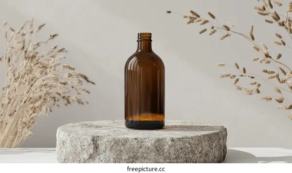 Amber Glass Bottle on Natural Stone Pedestal with Dried Grasses