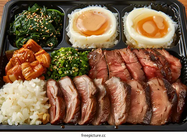 A delicious bento box with steak, eggs, rice, and vegetables