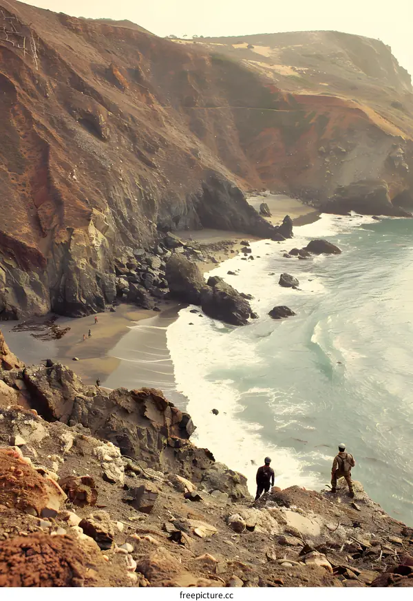 Two People Standing on a Cliff Overlooking the Ocean and a Sandy Beach