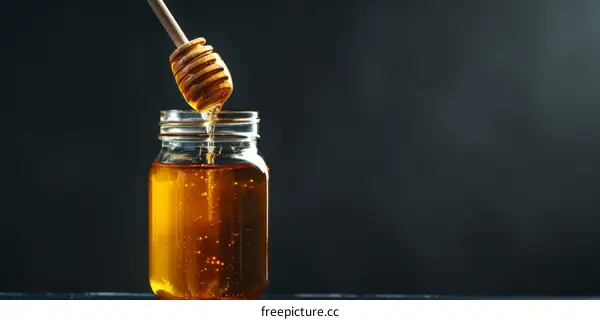Delectable Honey Dripping from a Wooden Dipper into a Glass Jar