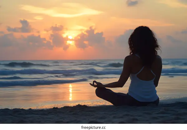 Silhouette of a Woman Meditating on the Beach at Sunset