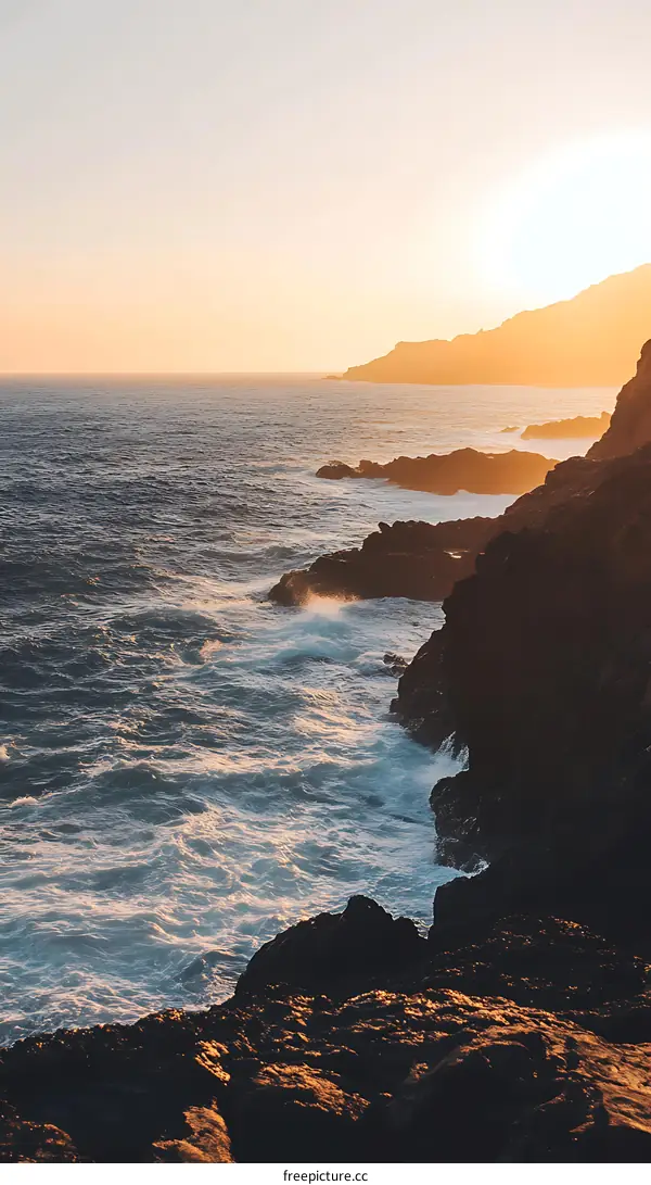 Ocean Waves Crashing Against Rocky Coastline at Sunset