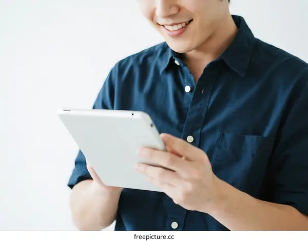 Young man using a white tablet device with a smile