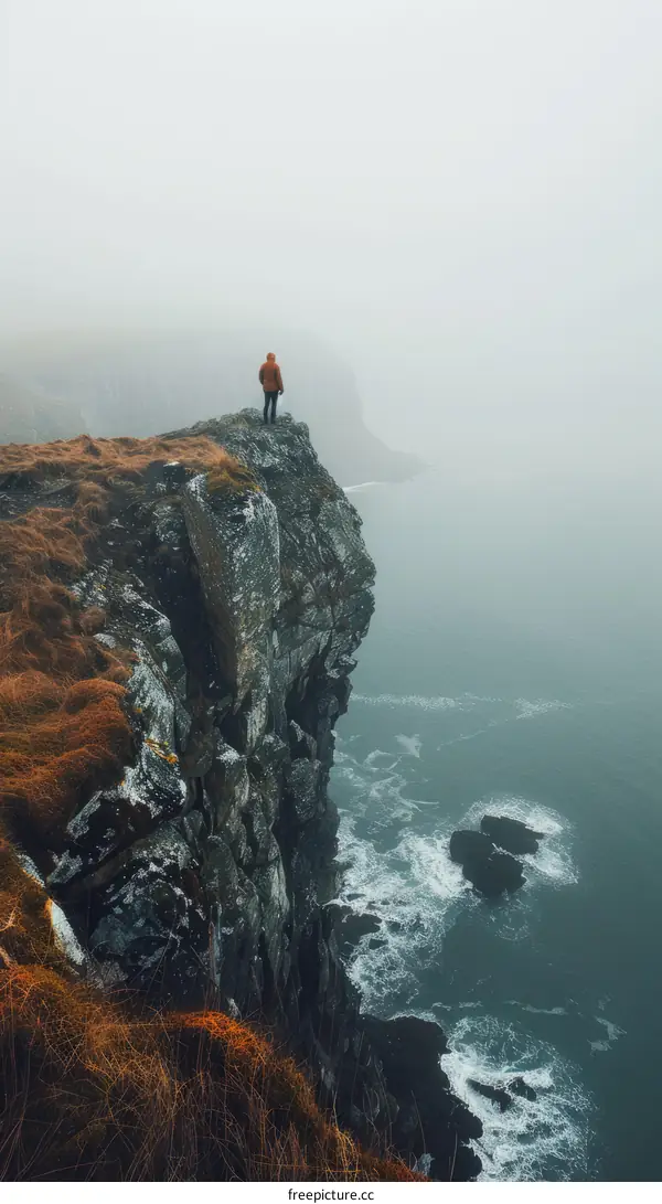 Man standing on a cliff overlooking the ocean