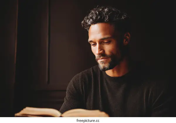 Focused Man Reading a Book in a Dark Room