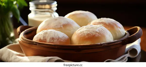 A wooden bowl filled with freshly baked bread rolls
