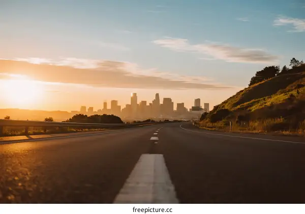Sunset view of an empty road leading to a city skyline