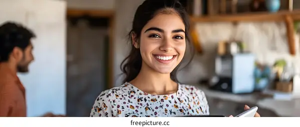 Smiling Woman Holding Phone in Kitchen