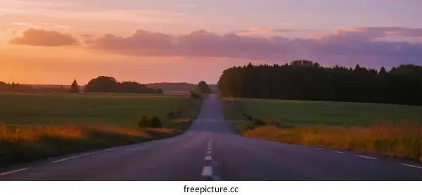 A peaceful road stretching under a colorful sunset sky