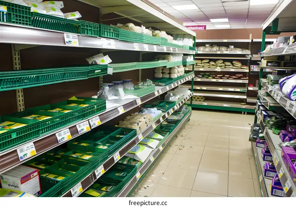 Empty Supermarket Shelves with Green Baskets and Food Items