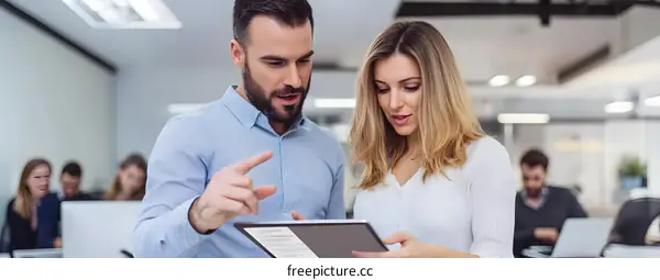 Two Business Colleagues Discussing Project On Tablet In Office