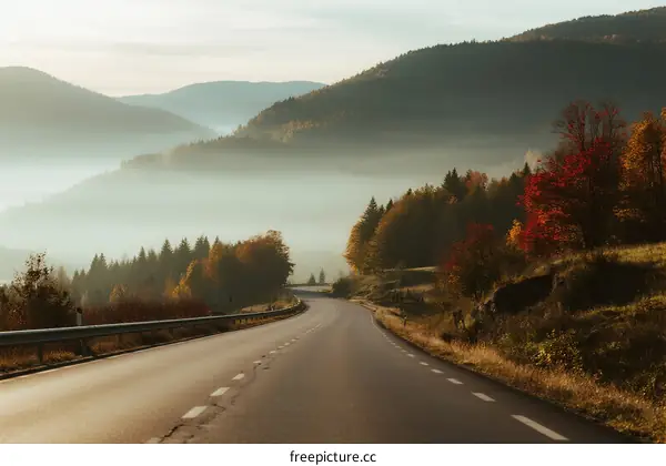 A winding road surrounded by misty mountains and colorful trees