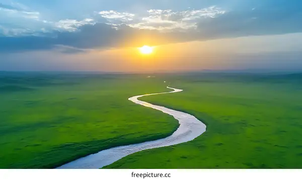 Sunrise over a winding river in a lush green meadow