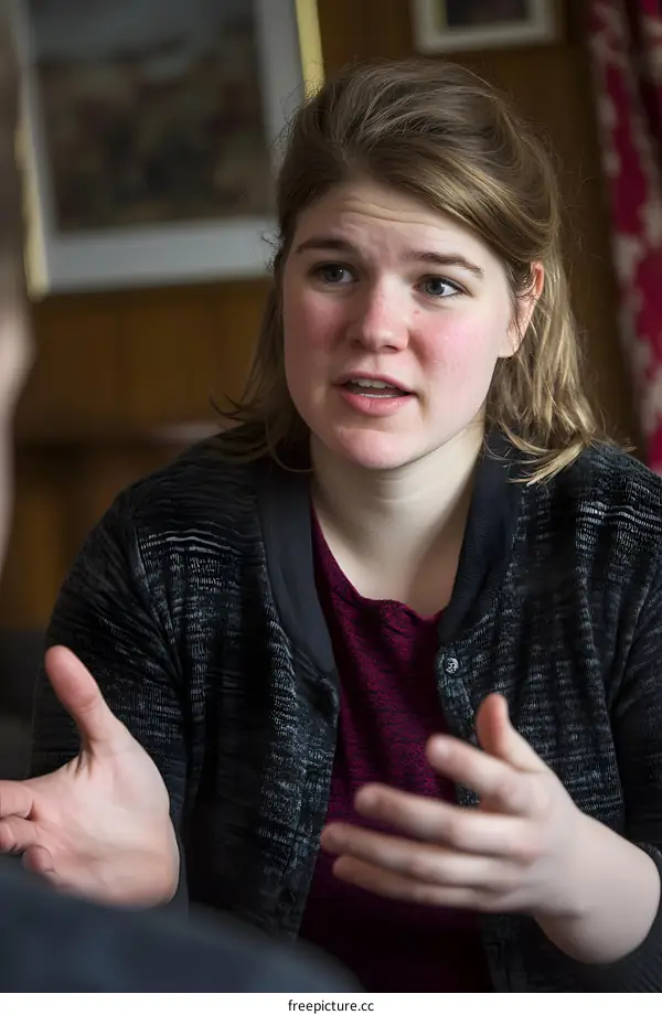 Young Woman Talking to Someone Sitting in Front of Her