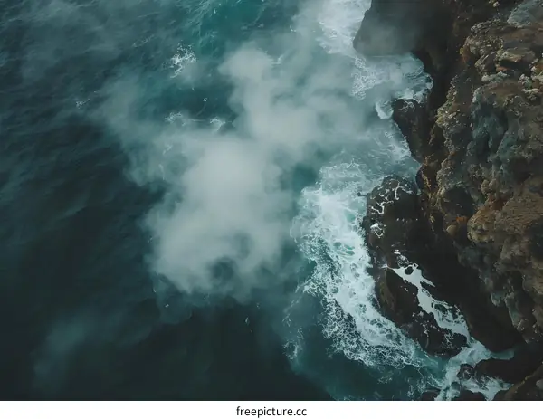 Aerial View of Ocean Waves Crashing Against Rocky Cliff