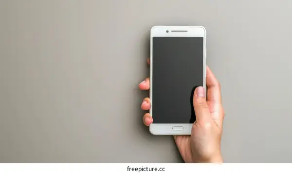 A hand holding a white smartphone from the top view