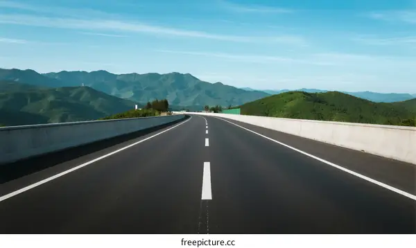 A smooth asphalt road extending into the distance with mountain views