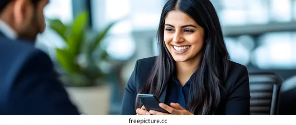 Smiling Businesswoman Looking at Smartphone in Office
