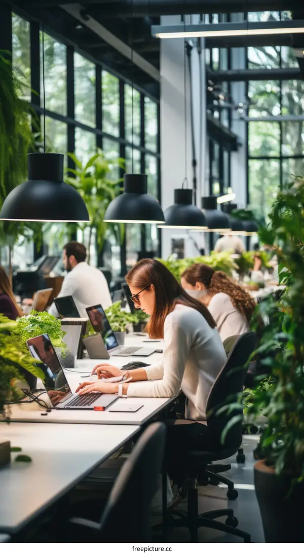 Focused businesswoman working on laptop in modern green office
