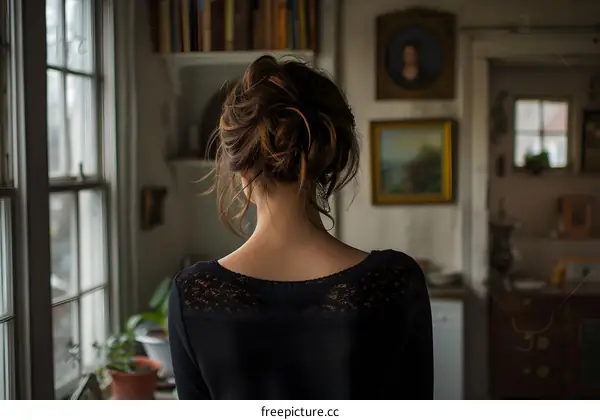 Woman with a Bun Looking Out a Window in a Room