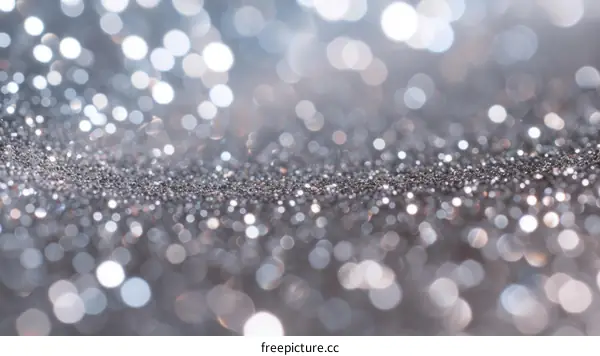 Silver glitter sparkles on a shiny surface