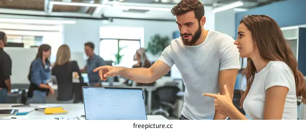 Two Colleagues Discussing Project on Laptop in Office