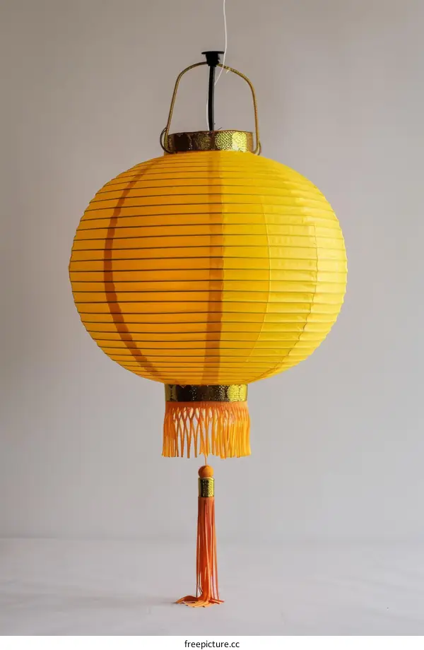Round yellow paper lantern with red tassel hanging from it
