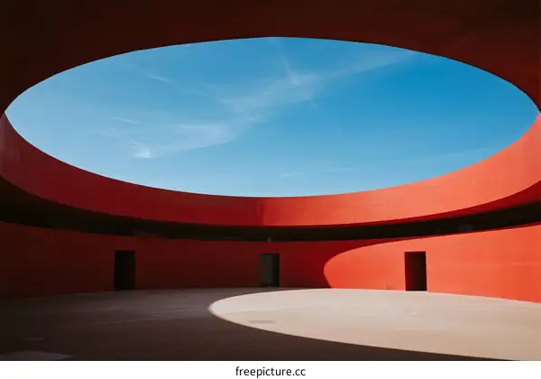 A Circular Red Architectural Structure with Open Ceiling Under Blue Sky
