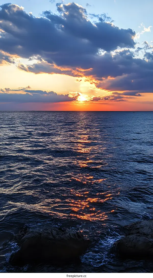 Sunset over the Ocean with Clouds and Rocks