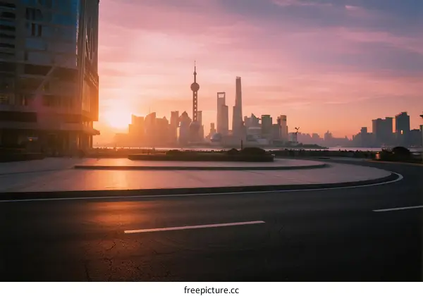 Sunrise over modern city skyline with empty road in foreground