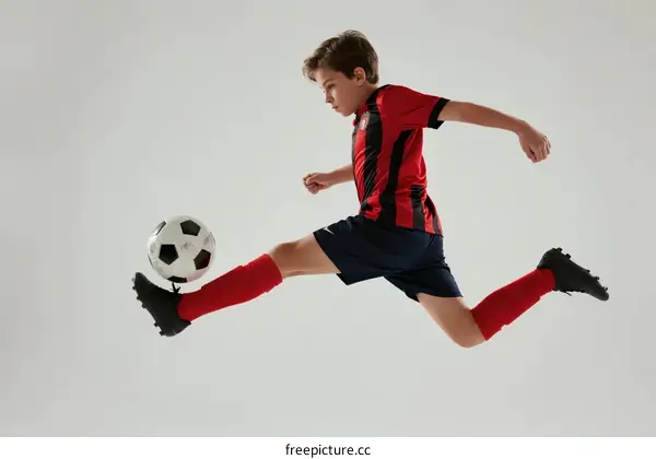Young boy in soccer uniform kicking a soccer ball