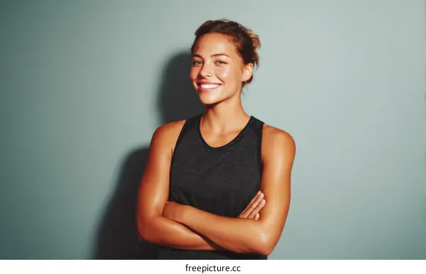 Smiling woman with crossed arms standing against gray background