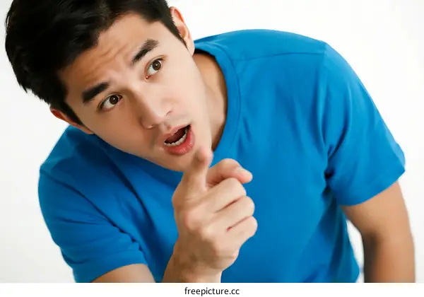 A man in blue shirt pointing with finger and making an expression