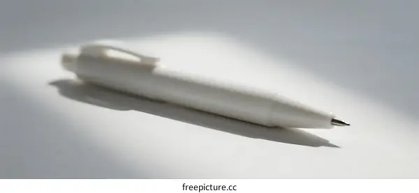 A close-up view of a white ballpoint pen on a light surface