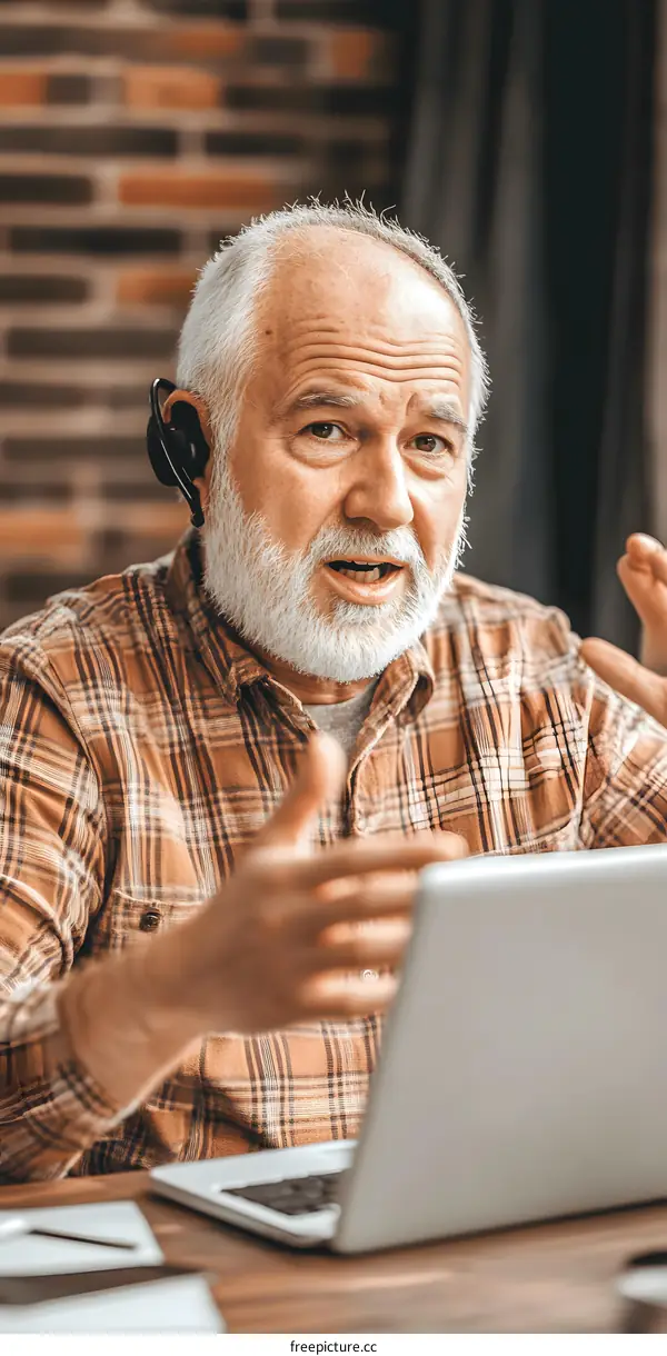 Senior Man Talking on Laptop with Headset
