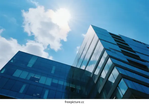 Modern glass building under a bright blue sky with sunlight