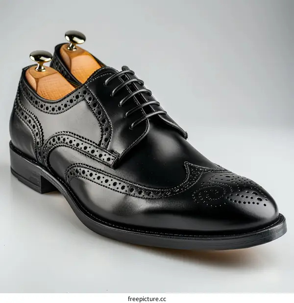 Black leather wingtip brogue shoes with brown wooden shoe trees