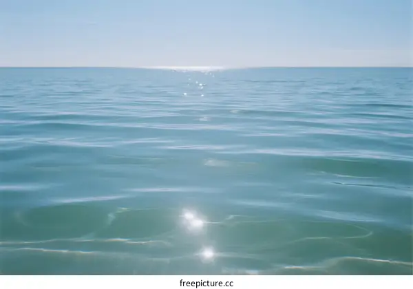 The sun reflects on the calm blue ocean surface