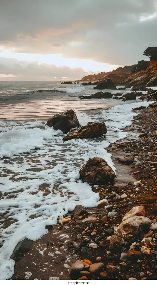 Sea Shore with Rocks and Foamy Waves During Sunset