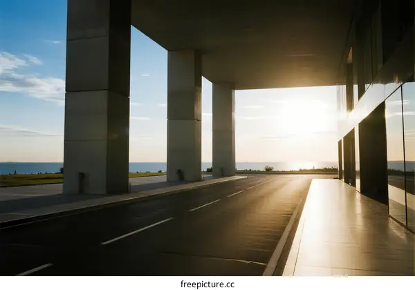 Sunlit modern building with empty road and sea view