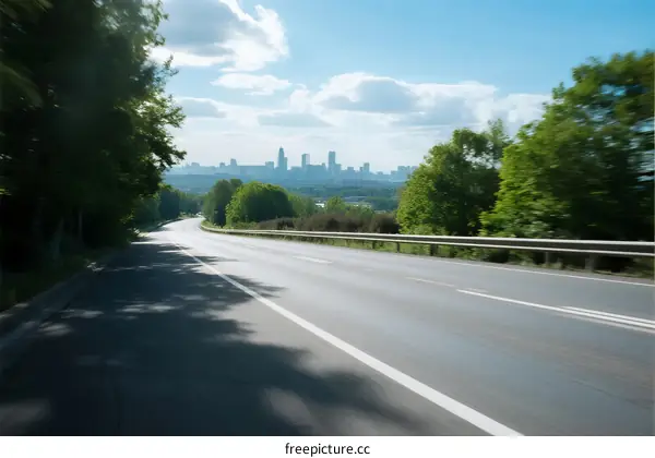A scenic road with trees on both sides leading to a city skyline