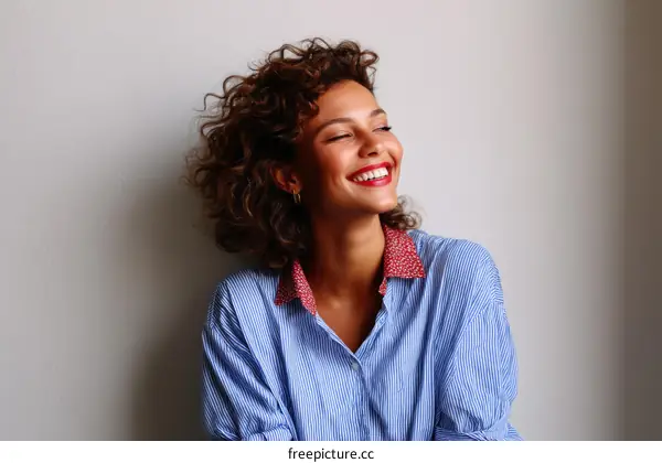 Smiling Woman in a Striped Shirt against a Light Grey Wall