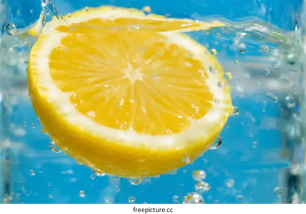 Sliced Lemon Falling into Clear Water with Bubbles