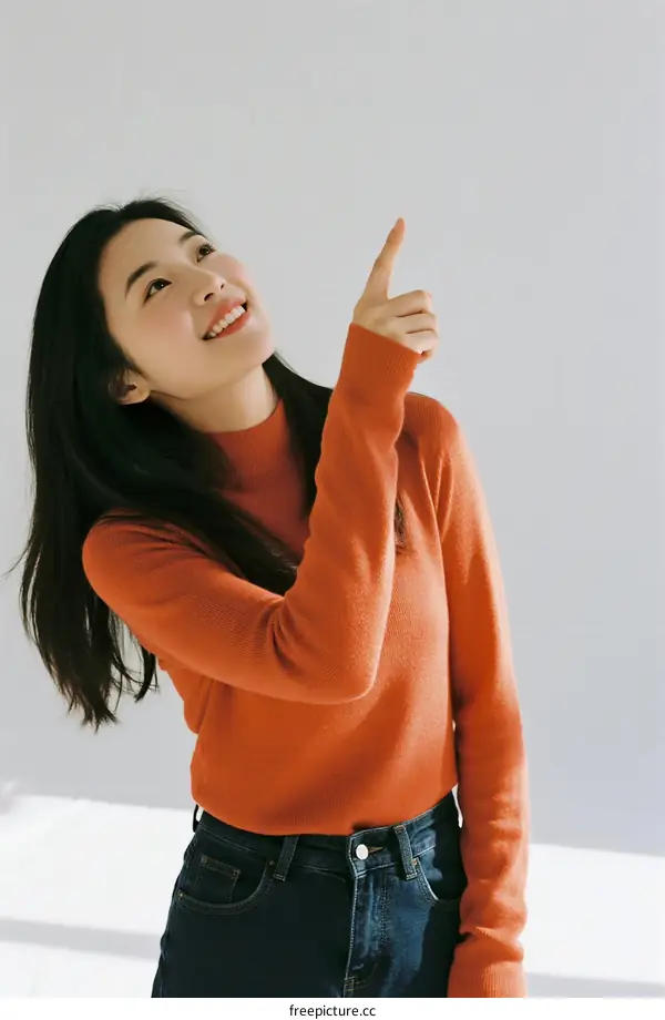 A Young Woman in Orange Sweater Pointing Upward