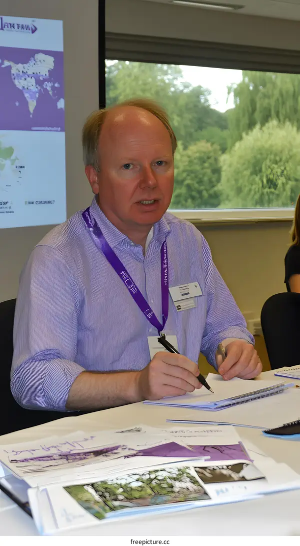 Man in Blue Shirt Writing in Notebook at Conference